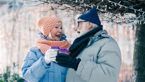 Starší pár sedí na lavičke v parku, jeden z nich drží fľašu vína.