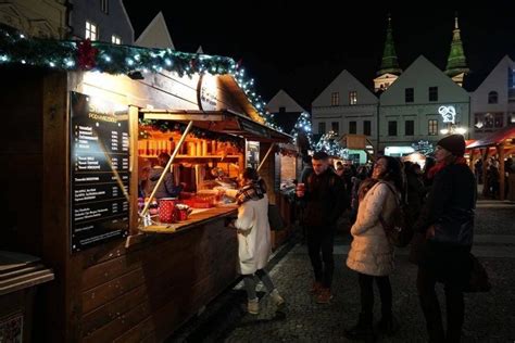 Ľudia popíjajúci horúce nápoje na vianočných trhoch v zasneženom meste