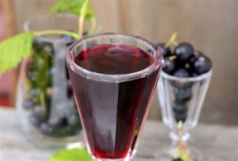 Sklenný pohár plný čiernych ríbezlí zaliatych alkoholom